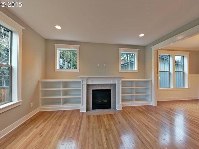2437 North Alberta Street Portland, OR 97217 - Photo 11 of 16 an empty room with wooden floor fireplace and windows