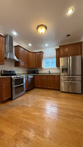 a kitchen with stainless steel appliances granite countertop a stove top oven a sink and a refrigerator