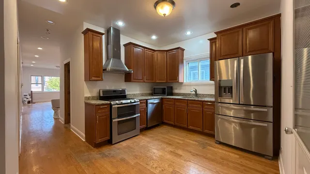 a kitchen with stainless steel appliances granite countertop a refrigerator a stove and a sink