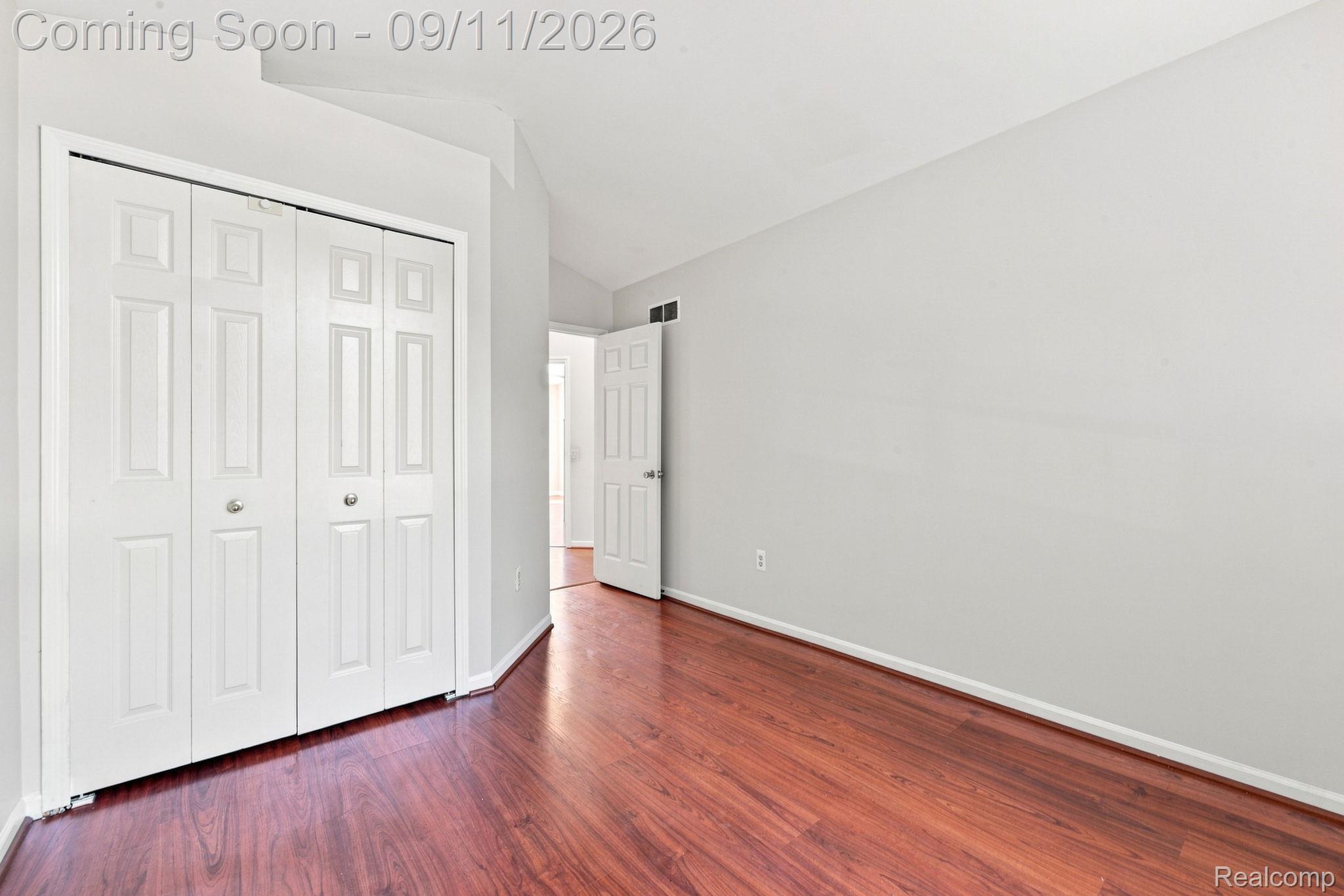 3201 Lynhurst Court Rochester, MI 48306 - Photo 26 of 43 Spacious bedroom featuring rich wood-finish flooring, abundant natural light from large closet doors, and crisp white painted walls with clean architectural detailing