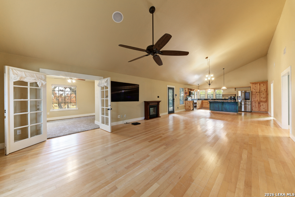 451 Wegener Trail Fischer, TX 78623 - Photo 8 of 43 a view of a livingroom with a kitchen and a stove wooden floor a ceiling fan and a window