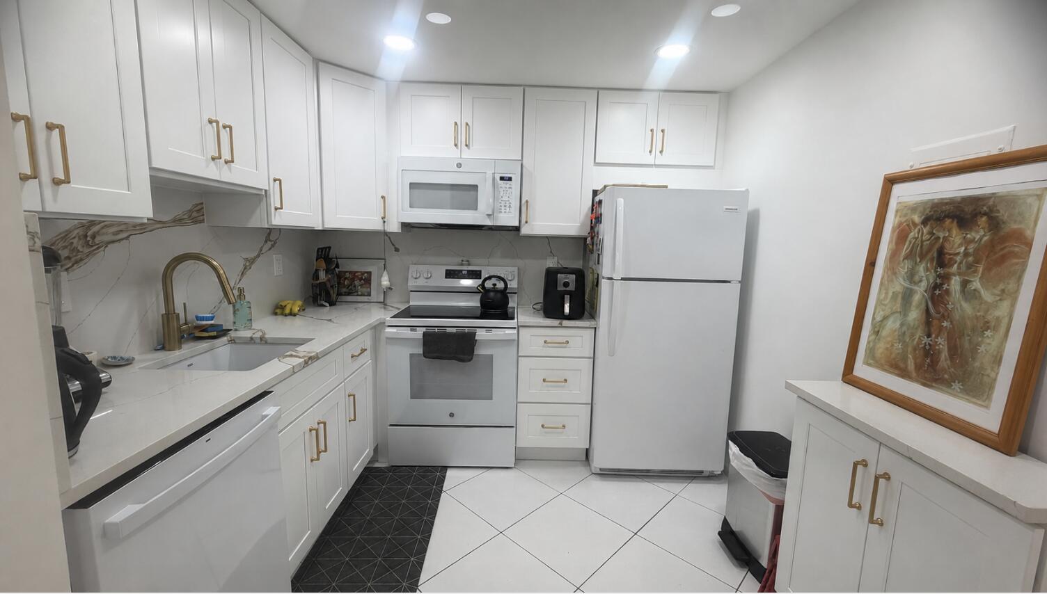 930 Normandy Trail Delray Beach, FL 33484 - Photo 3 of 34 a kitchen with white cabinets and white appliances