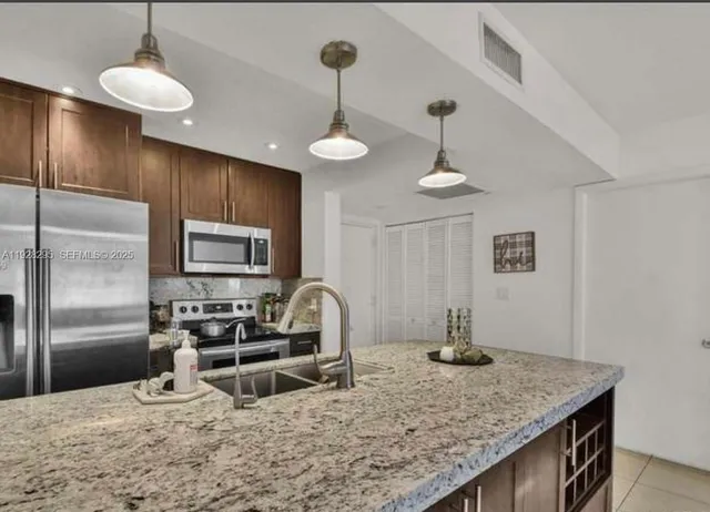 a kitchen with stainless steel appliances granite countertop a sink refrigerator and cabinets