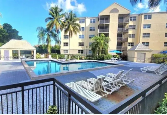a view of a patio with couches table and chairs under an umbrella with palm trees