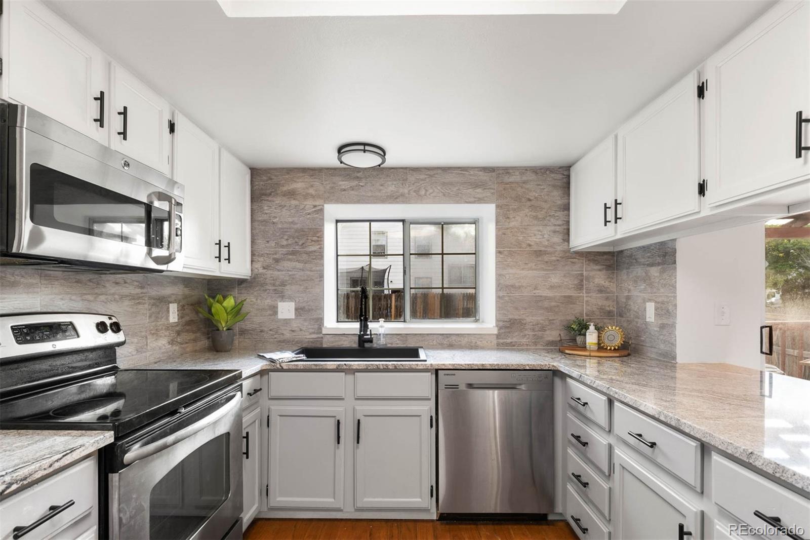 6283 Xavier Street Arvada, CO 80003 - Photo 10 of 36 a kitchen with stainless steel appliances white cabinets and a sink