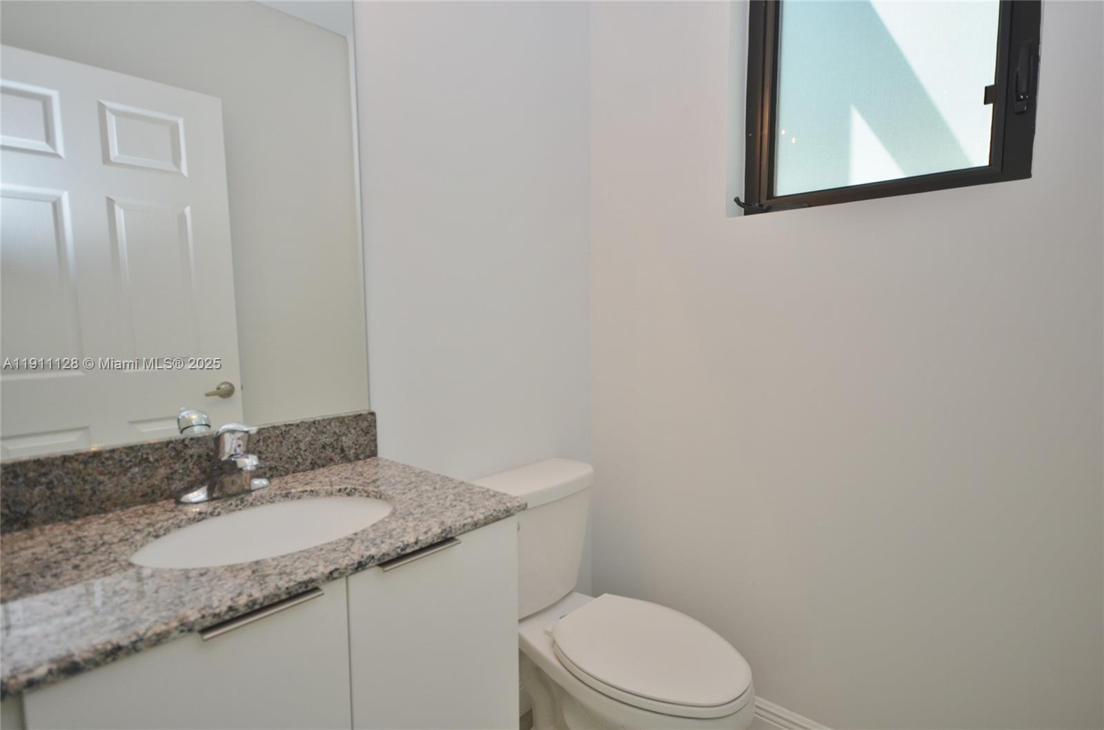 4374 East 10th Avenue, Unit 4374 Hialeah, FL 33013 - Photo 22 of 29 a bathroom with a granite countertop sink and a mirror