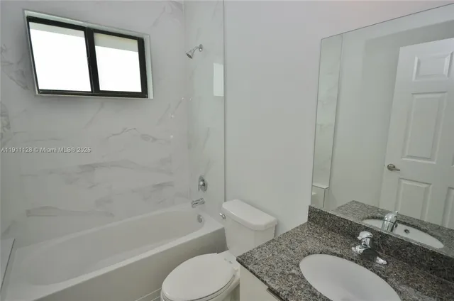 a bathroom with a granite countertop sink toilet a mirror and a bathtub