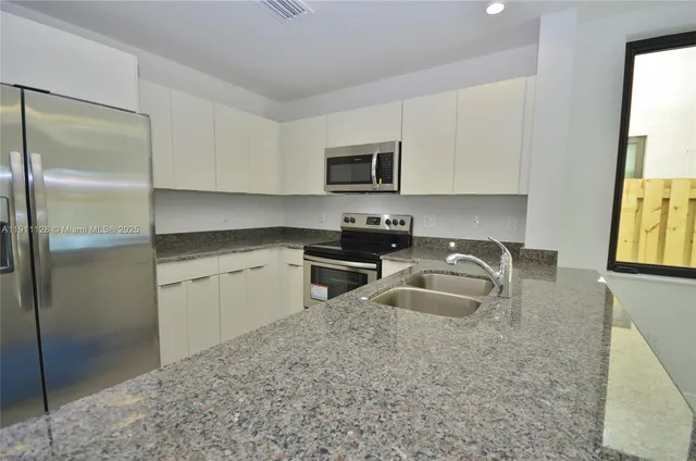 a kitchen with granite countertop a sink stove and refrigerator