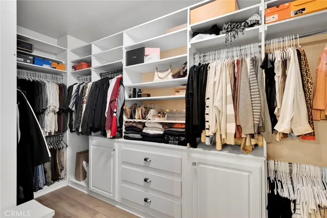 a view of walk in closet with clothes and shoes