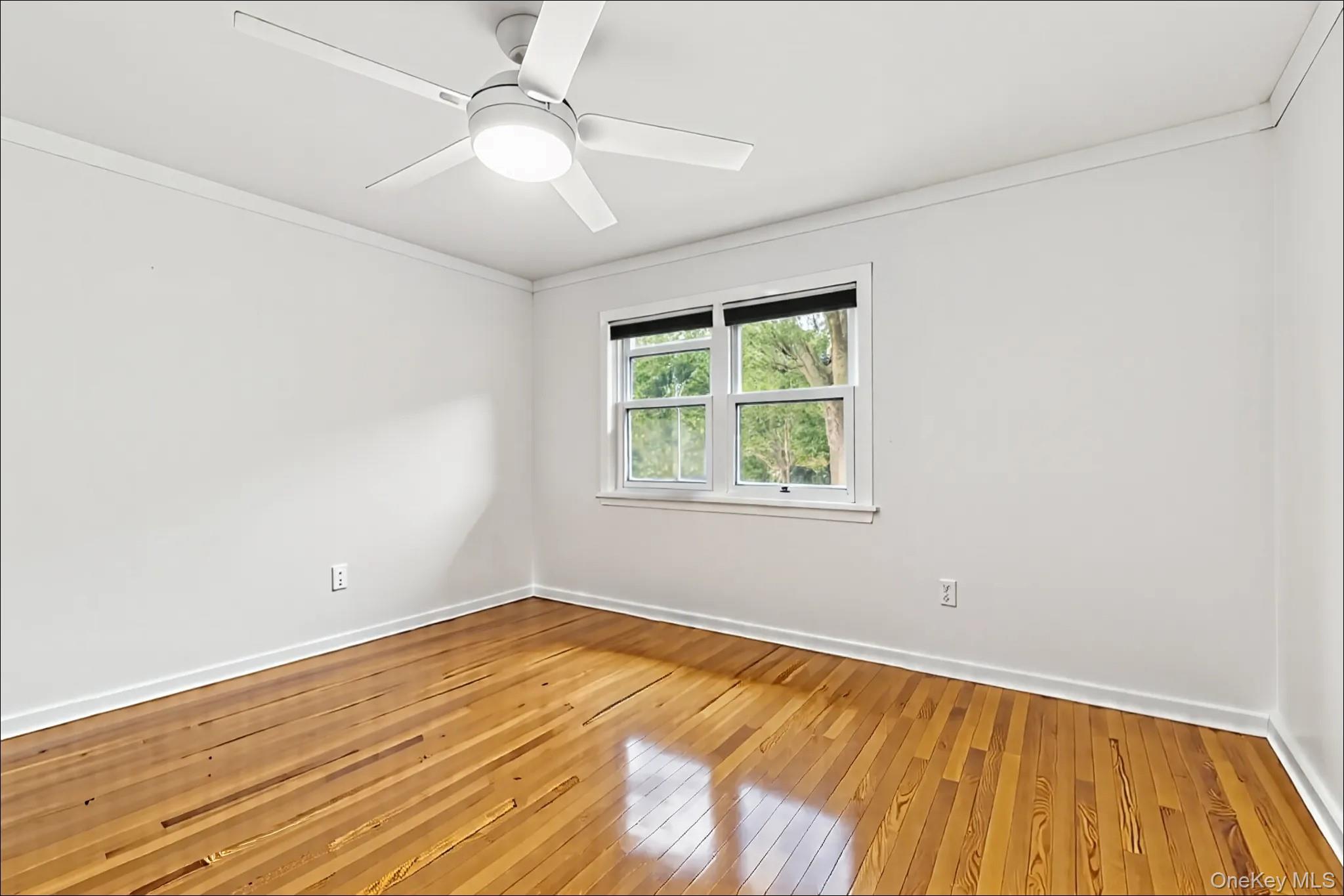 370 Blue Point Road Farmingville, NY 11738 - Photo 15 of 19 Empty room featuring wood-type flooring, crown molding, and ceiling fan