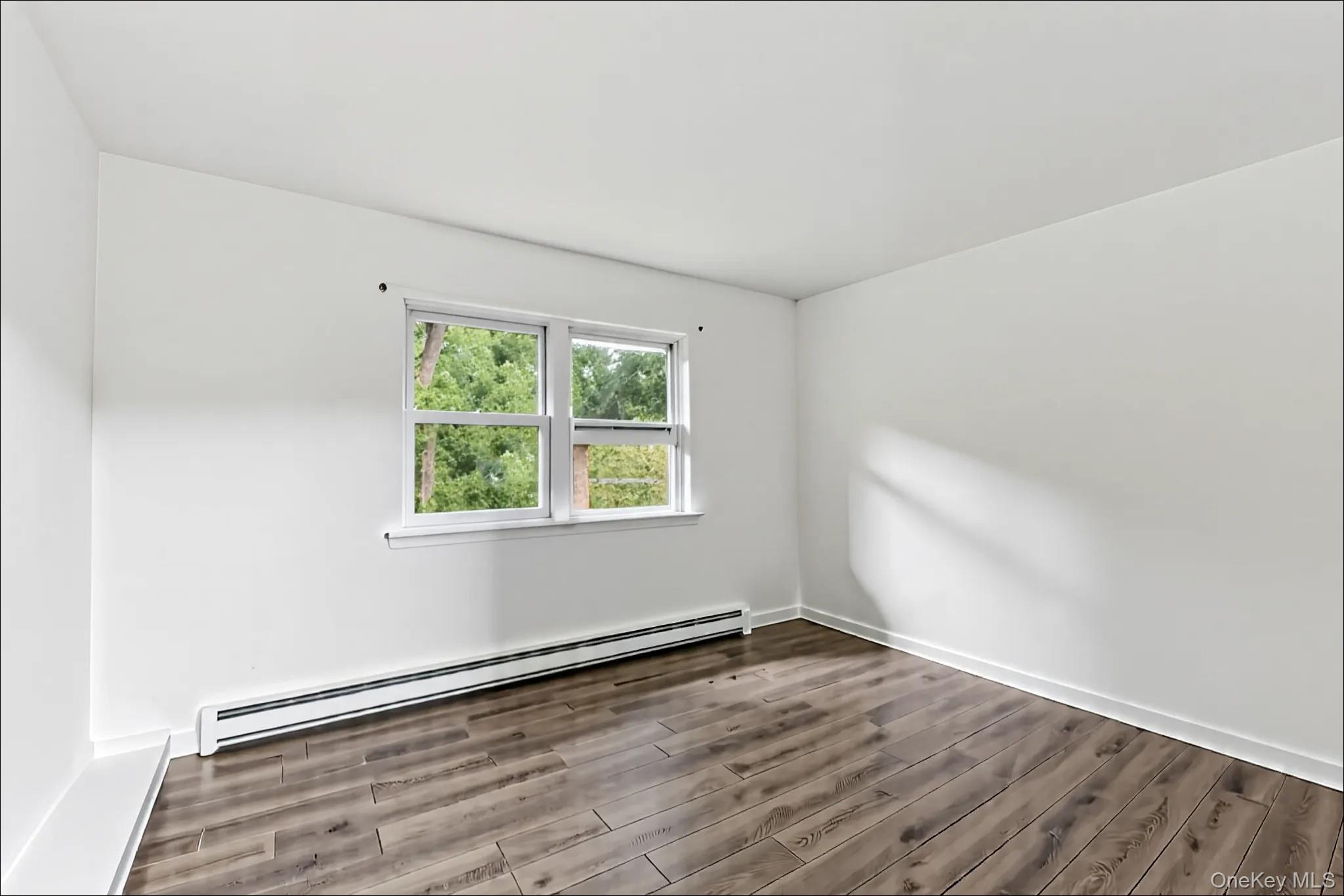370 Blue Point Road Farmingville, NY 11738 - Photo 17 of 19 Empty room with a baseboard radiator and wood finished floors