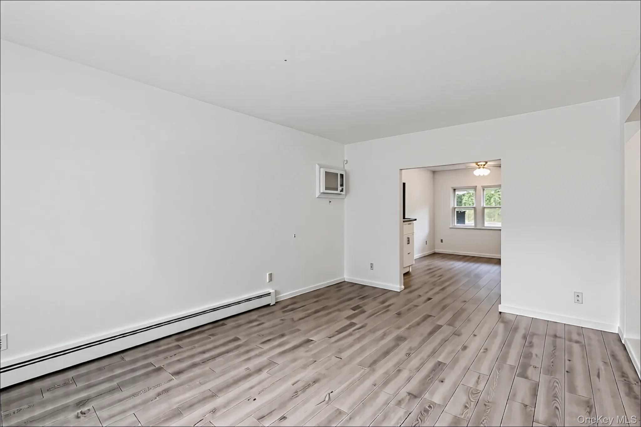370 Blue Point Road Farmingville, NY 11738 - Photo 5 of 19 Spare room with a baseboard heating unit, light wood-style floors, and a wall mounted air conditioner