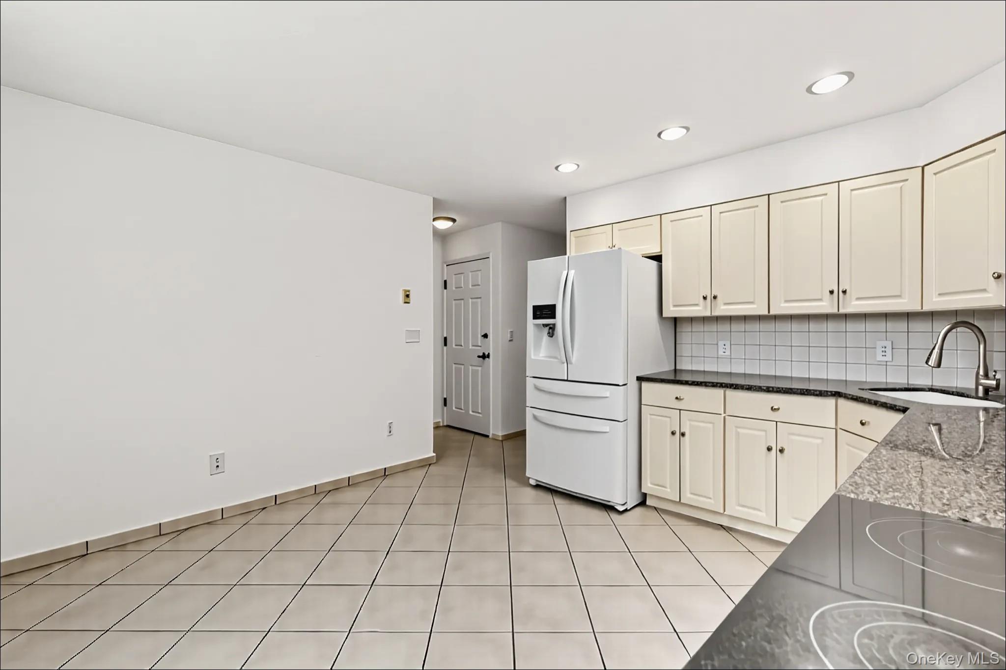 370 Blue Point Road Farmingville, NY 11738 - Photo 6 of 19 Kitchen featuring white fridge with ice dispenser, dark stone countertops, decorative backsplash, recessed lighting, and light tile patterned floors