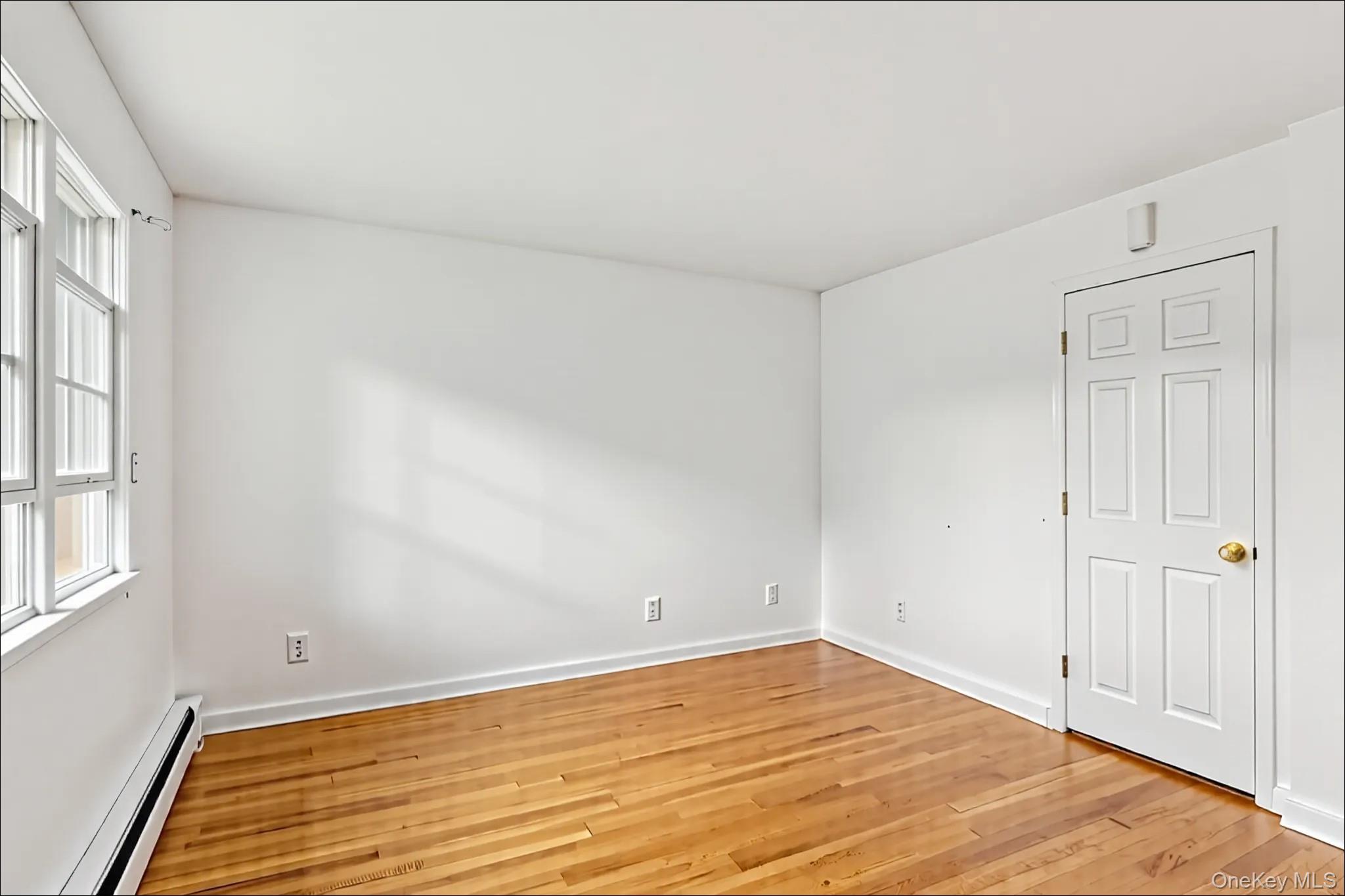 370 Blue Point Road Farmingville, NY 11738 - Photo 10 of 19 Spare room with a baseboard heating unit and light wood-type flooring