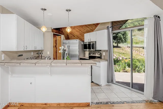 a kitchen with kitchen island a counter top a stove a sink cabinetry and a refrigerator