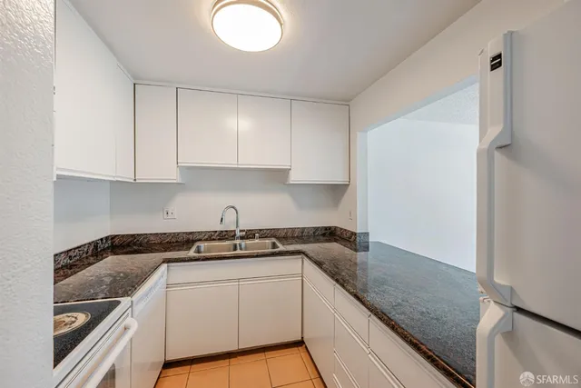 a kitchen with granite countertop a sink a stove and cabinets