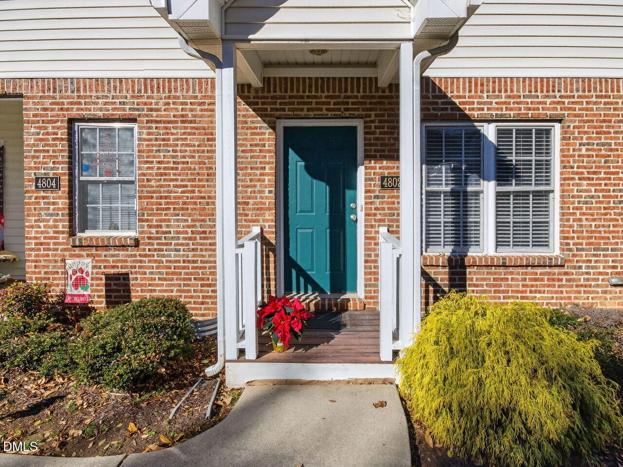 a view of a brick house with potted plants and a table and chair