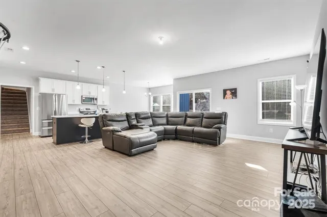a living room with furniture with kitchen view and a window
