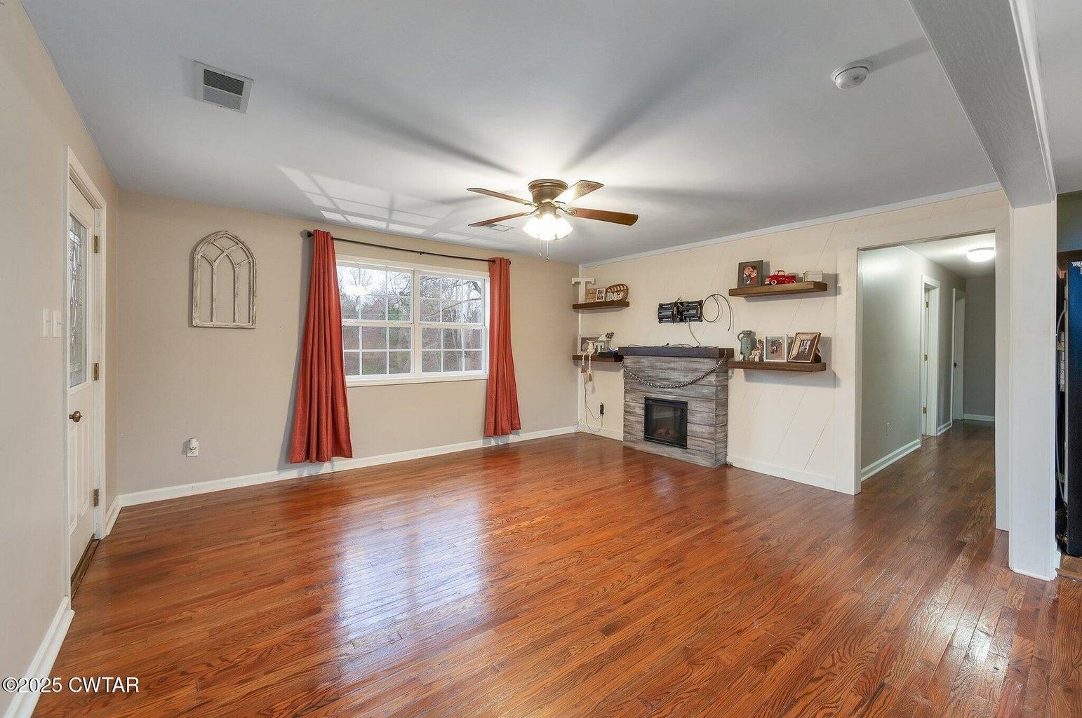 2510 Norton Road Middleton, TN 38052 - Photo 5 of 20 Unfurnished living room featuring a stone fireplace, ceiling fan, and dark hardwood / wood-style flooring