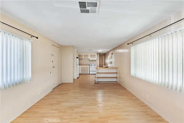 a view of empty room with wooden floor and fan