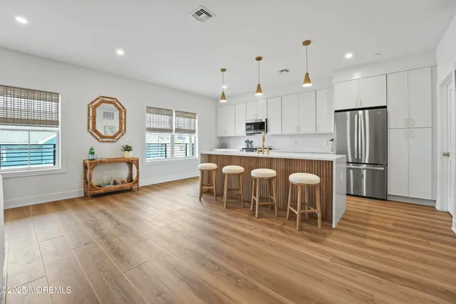 a kitchen with stainless steel appliances granite countertop a refrigerator a stove a sink a dining table and chairs with wooden floor