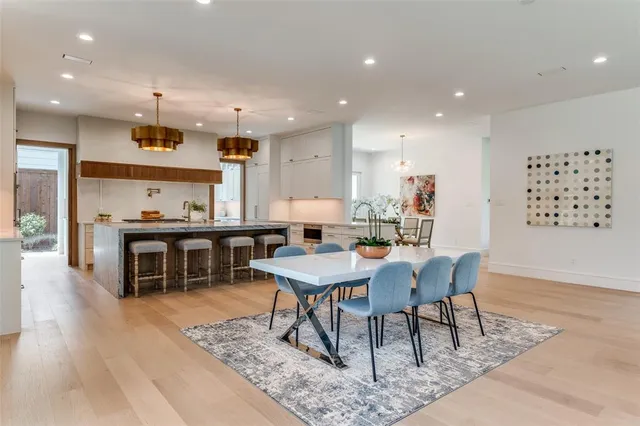 a large dining hall with stainless steel appliances granite countertop a stove a rug kitchen island a dining table and chairs