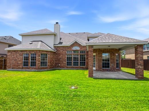 5034 West Fall Drive Midlothian, TX 76065 - Photo 37 of 40 Spacious backyard featuring a brick exterior, multiple large grid windows, a covered patio with brick columns, and a prominent chimney