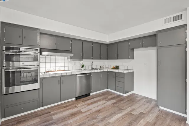 a kitchen with stainless steel appliances granite countertop a refrigerator and a stove top oven