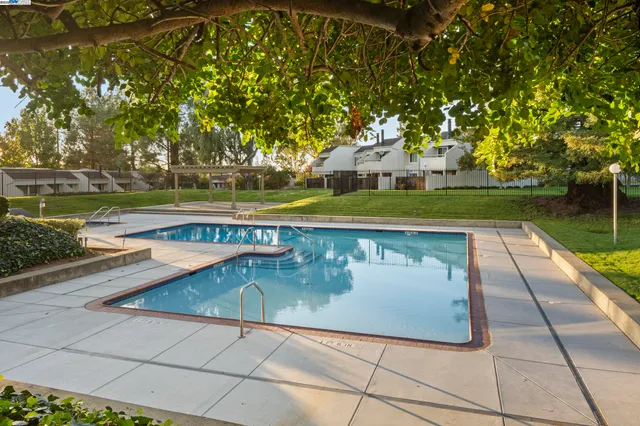 a view of swimming pool with sitting area and trees around