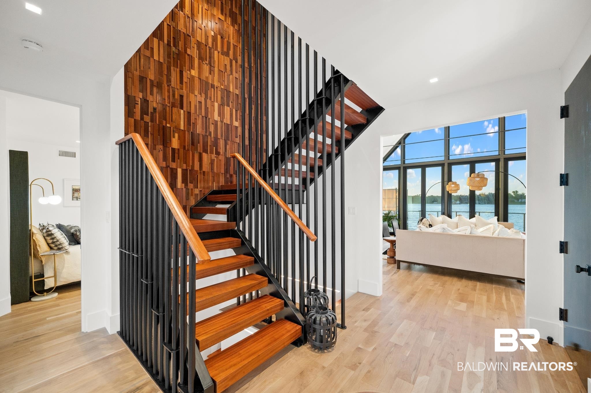 33349 River Road Orange Beach, AL 36561 - Photo 15 of 61 Staircase featuring wood treads, black vertical balusters, and a wood handrail against a wood-paneled accent wall