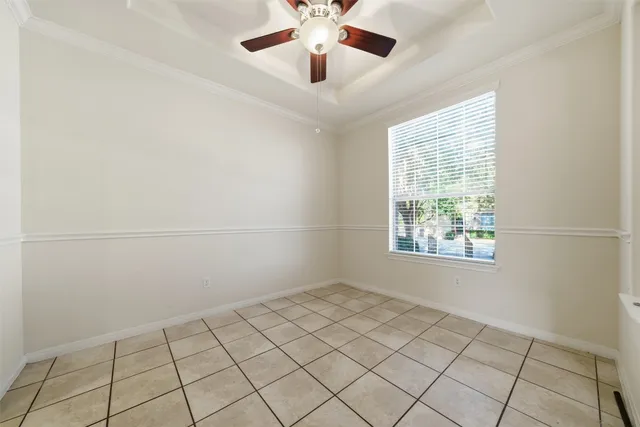 a view of an empty room with wooden floor and a chandelier fan