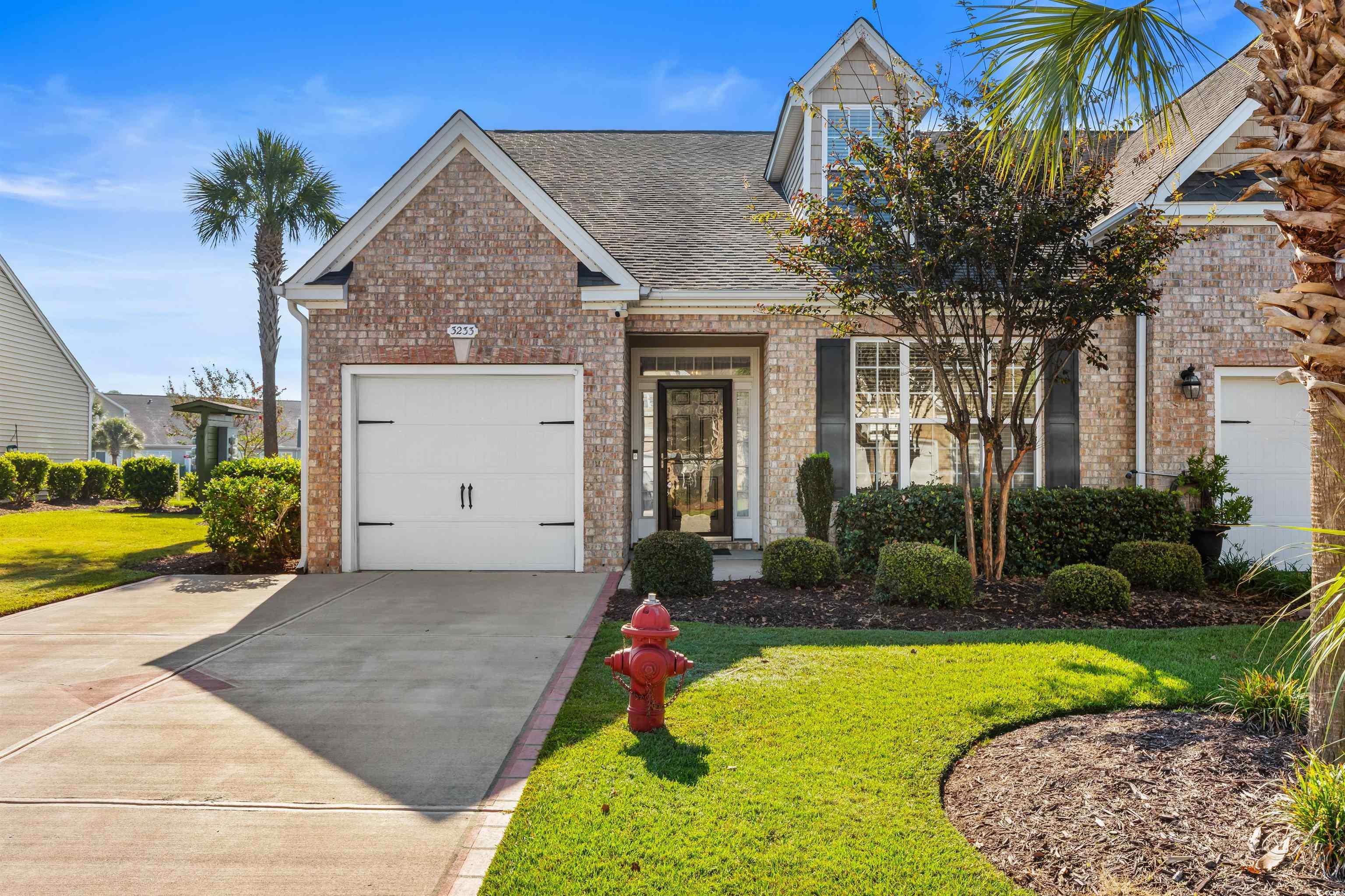 View of front of property featuring brick siding, roof with shingles, driveway, and a front yard