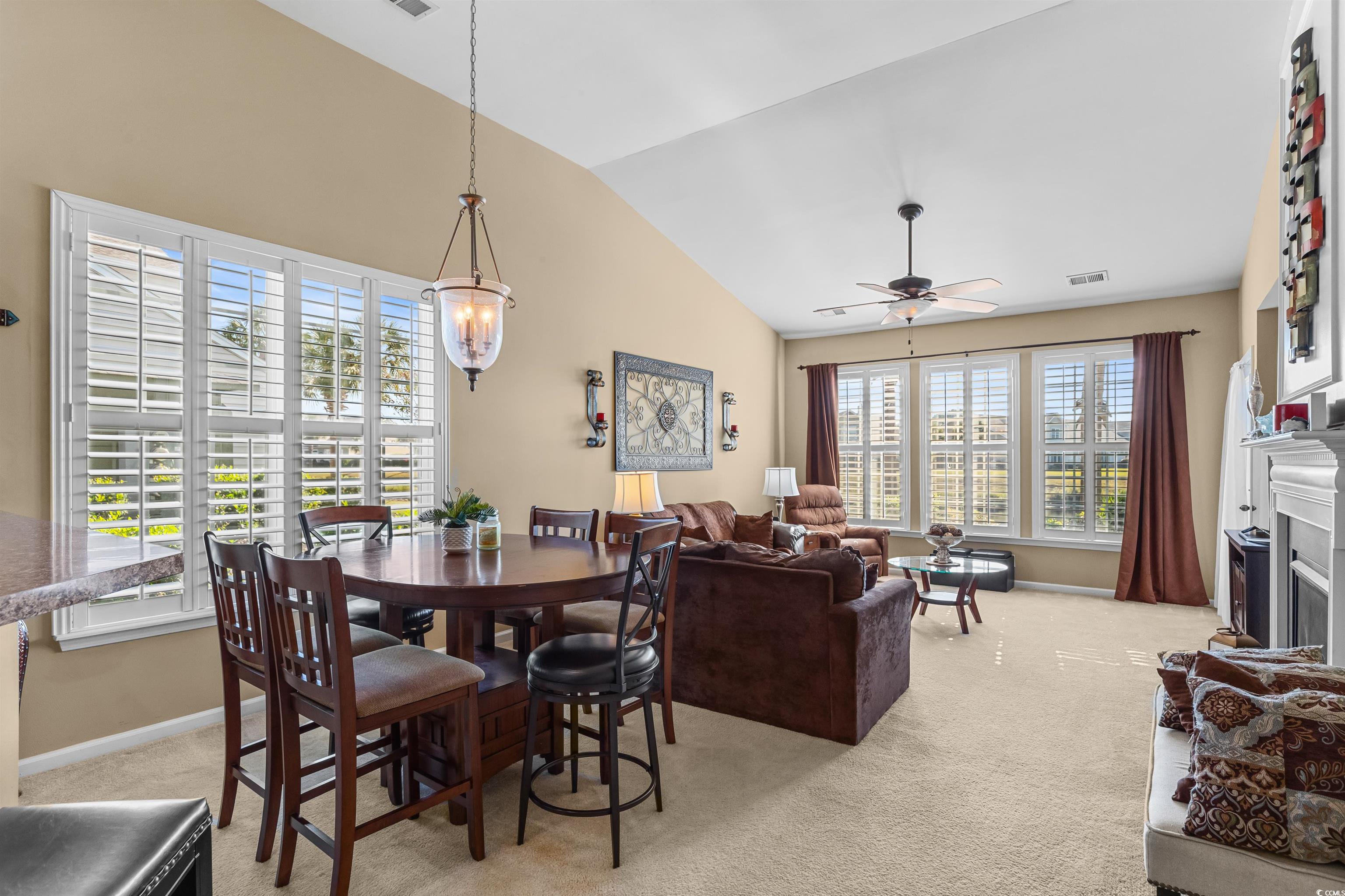 3233 Volterra Way, Unit 3233 Myrtle Beach, SC 29579 - Photo 14 of 40 Dining area with light carpet, lofted ceiling, a fireplace, and ceiling fan