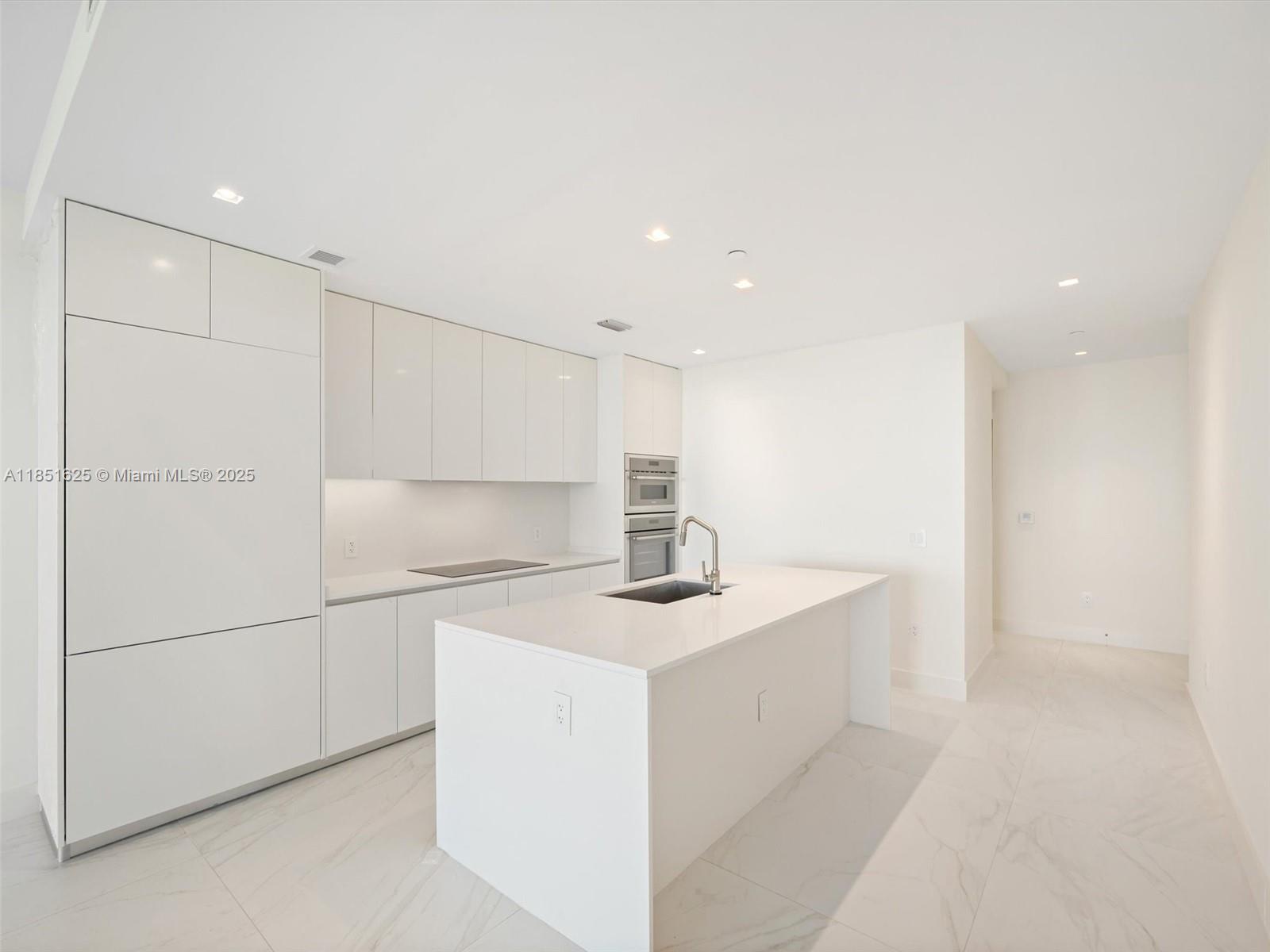 700 Northeast 24th Street, Unit 4305 Miami, FL 33137 - Photo 9 of 54 a kitchen with a sink a refrigerator and white cabinets