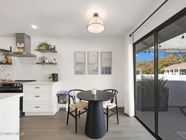 a kitchen with stainless steel appliances kitchen island granite countertop a table chairs in it and wooden floors