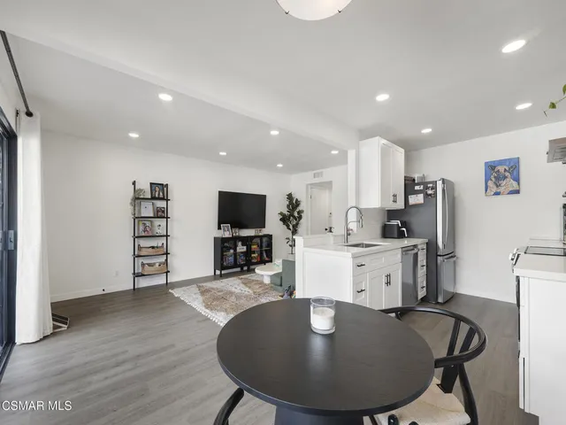 a kitchen with sink a refrigerator and chairs