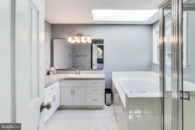 a spacious bathroom with a double vanity sink mirror and bathtub