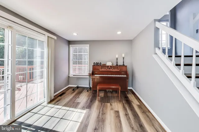 a room with wooden floor stairs and a piano