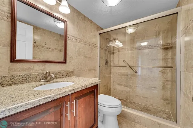 a bathroom with a granite countertop sink toilet and shower