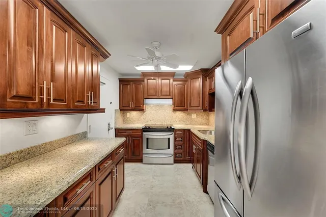 a kitchen with stainless steel appliances granite countertop a refrigerator a sink and a stove