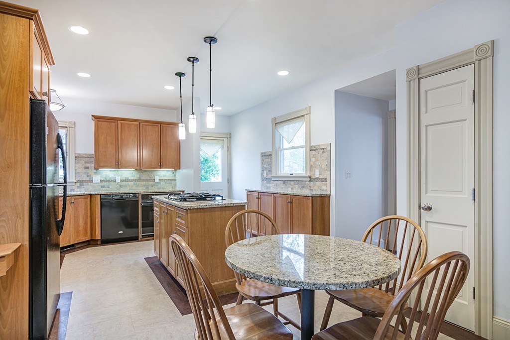 7 Raymond Street Lexington, MA 02421 - Photo 9 of 22 a kitchen with stainless steel appliances granite countertop a stove a sink dishwasher a dining table and chairs with wooden floor