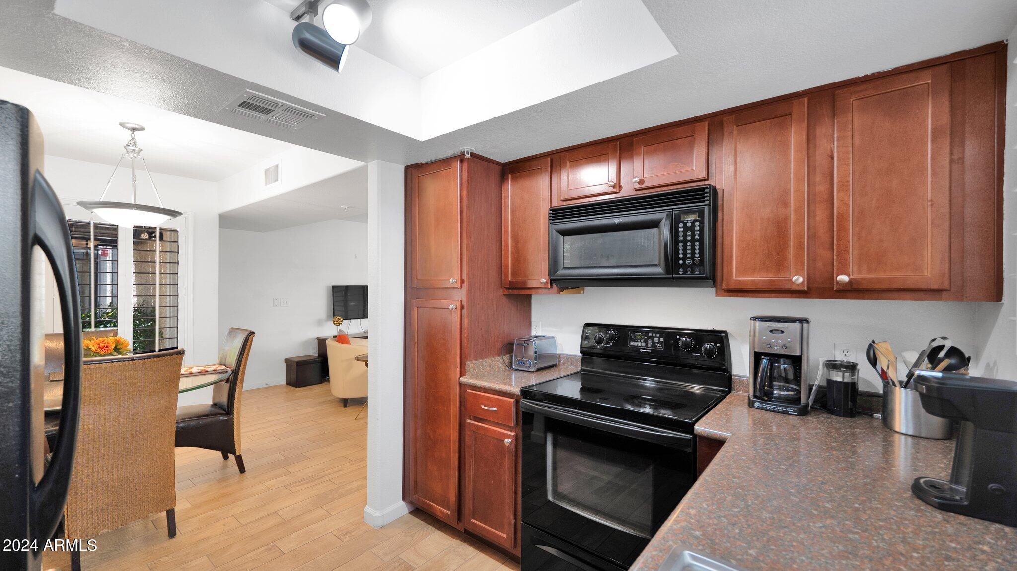 9990 North Scottsdale Road, Unit 1043 Paradise Valley, AZ 85253 - Photo 12 of 28 a kitchen with stainless steel appliances granite countertop a stove top oven a sink dishwasher a dining table and chairs with wooden floor