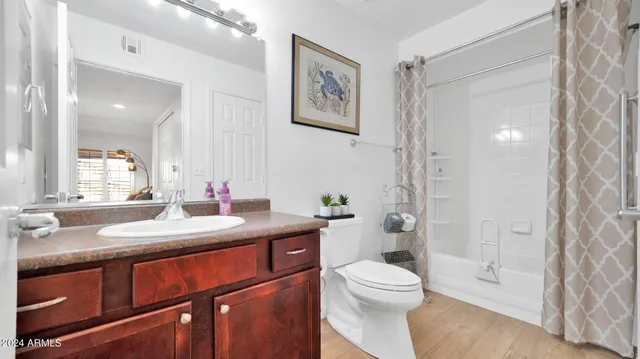 a bathroom with a granite countertop toilet a sink a mirror a vanity and shower