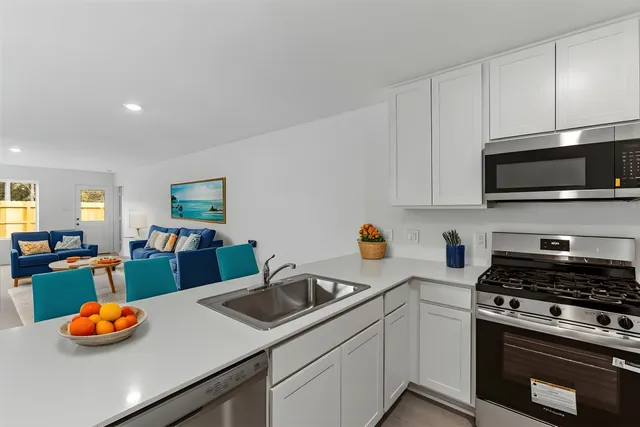 a kitchen with stainless steel appliances a stove a sink and a white cabinets