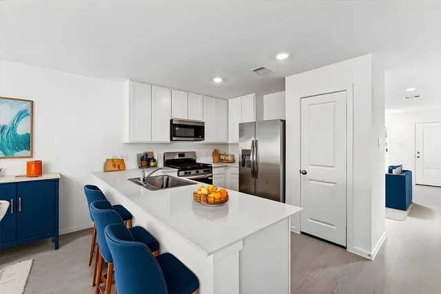 a kitchen with stainless steel appliances a refrigerator a sink a stove a table and chairs