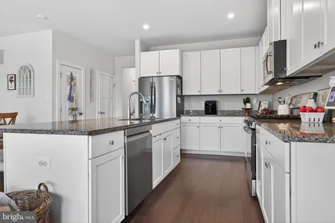 a kitchen with granite countertop a sink stove refrigerator and cabinets