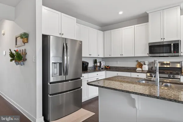 a kitchen with granite countertop a refrigerator and a stove top oven