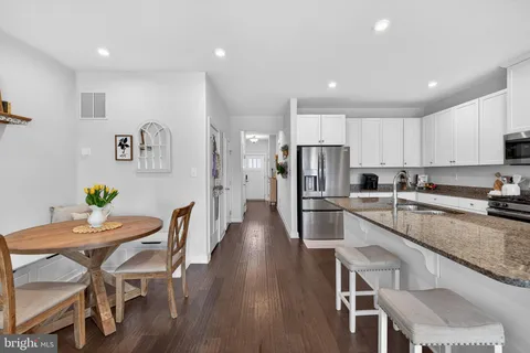 a kitchen with stainless steel appliances granite countertop a dining table chairs refrigerator and microwave