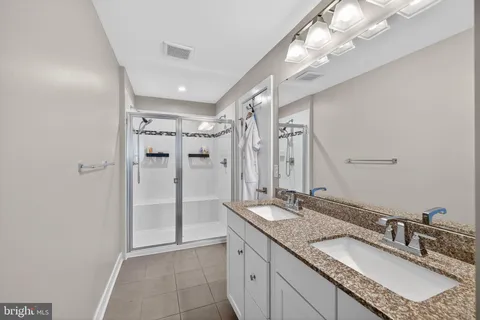 a bathroom with a granite countertop shower sink vanity and mirror