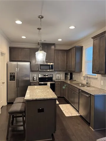 a kitchen with granite countertop a center island a sink stainless steel appliances and cabinets